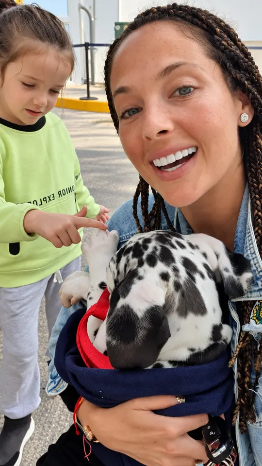 Una mujer y una niña acompañan a su cachorro arlequín.